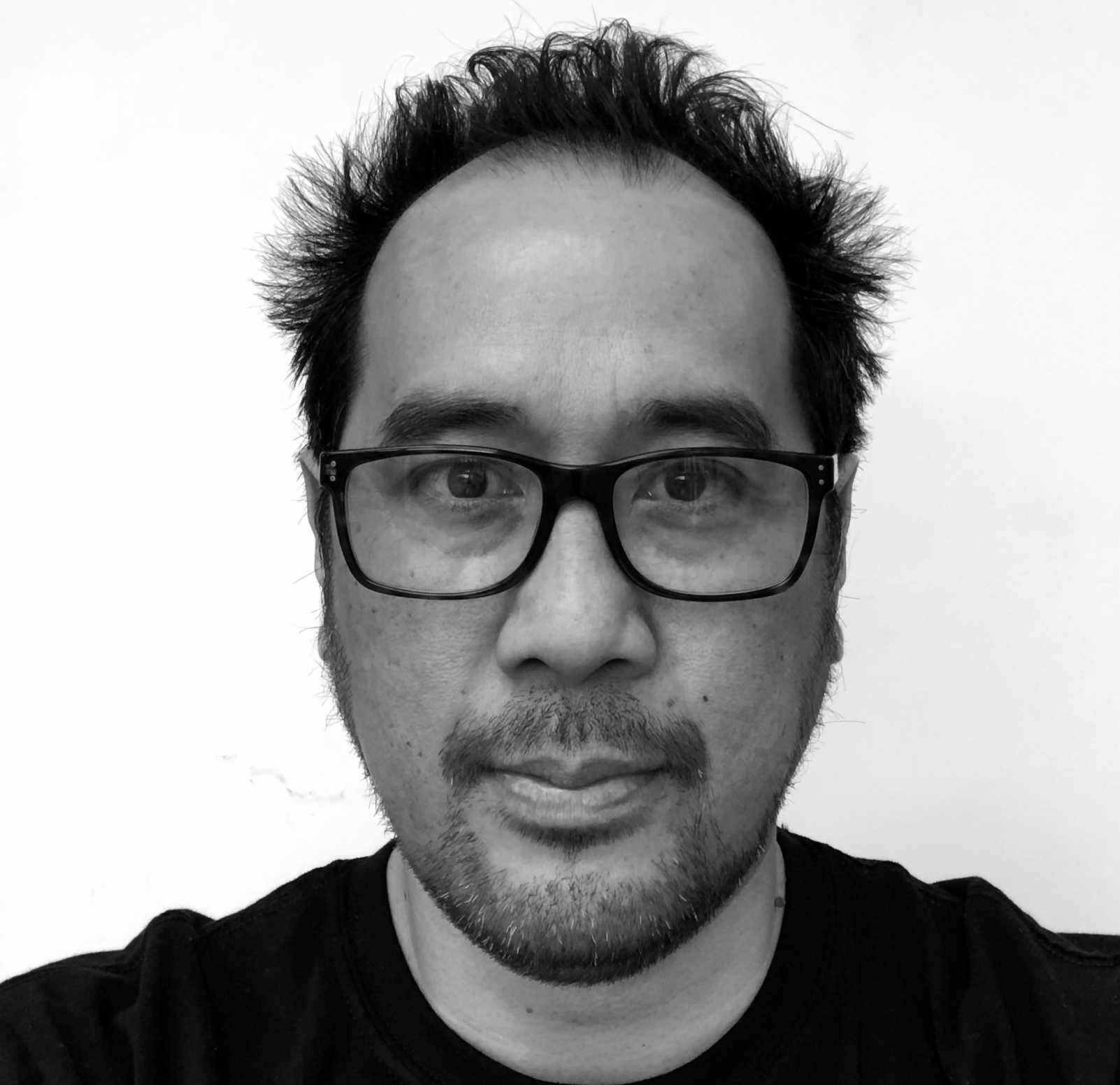 Jose Moran with a straight face in a bright room wearing a black t-shirt