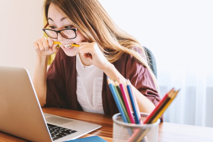 Woman looking stressed and biting on a pencil while she works from home