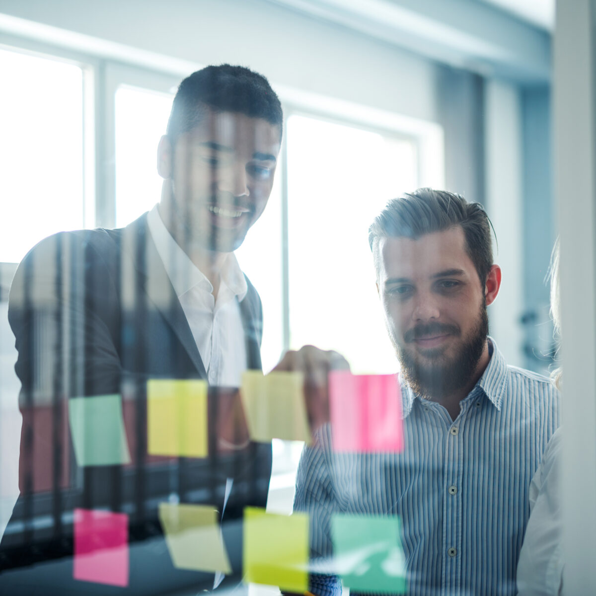 Two business men using post it notes to develop their company adoption Strategy