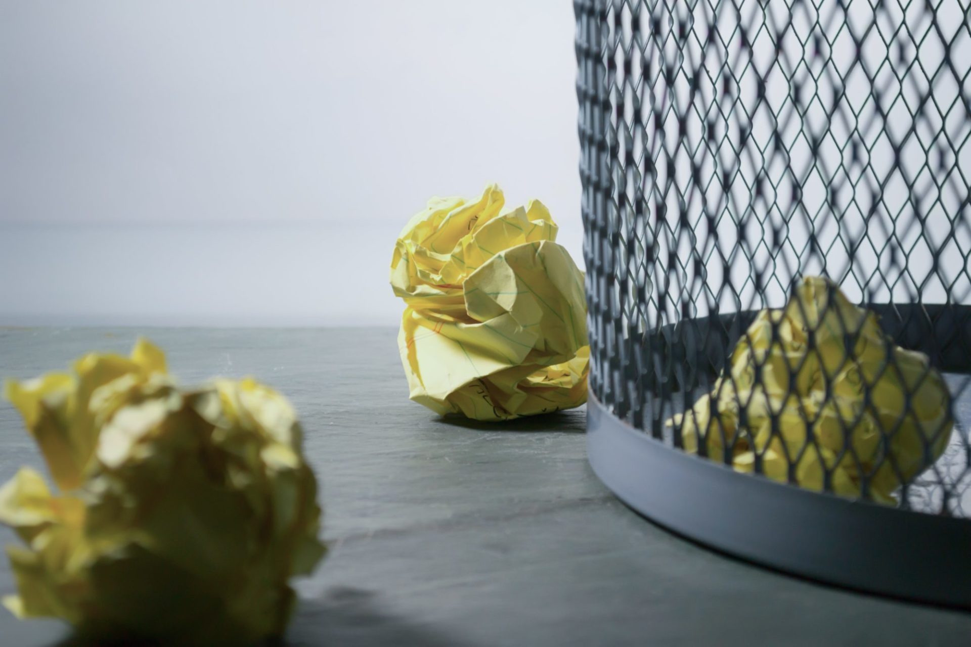 scrunched up notepad paper next to and in bin