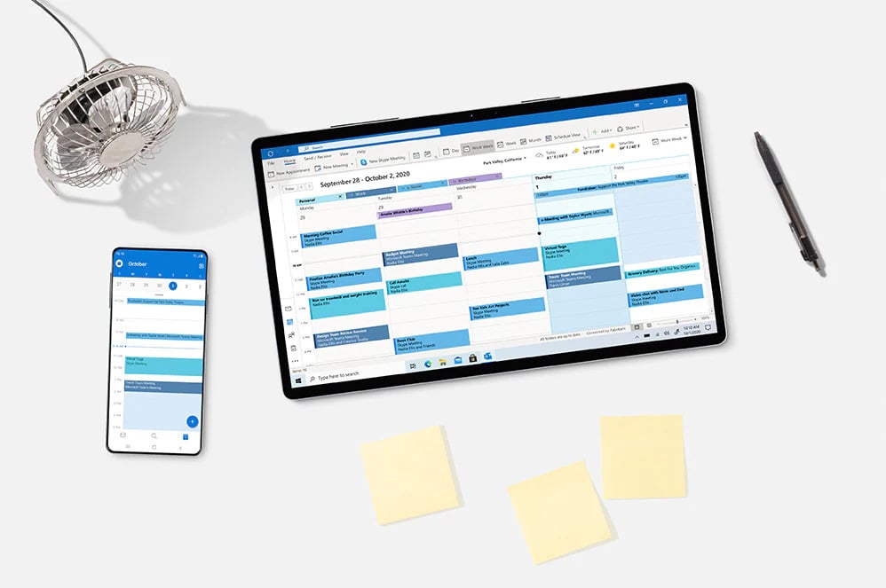 tablet and mobile with outlook calendar tablet and mobile phone on desk with outlook calendar open with a fan and pen
