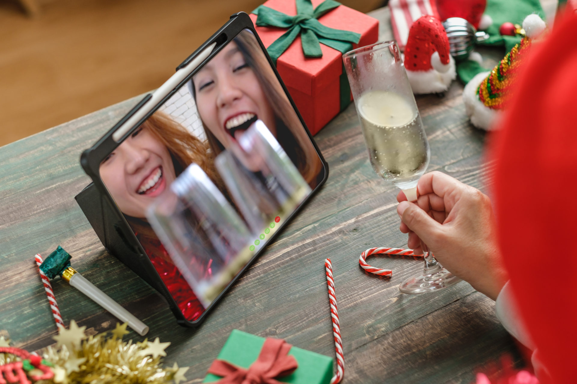 Two smiling women on a video call looking happy with drinks and a woman talking on call with a glass of champagne