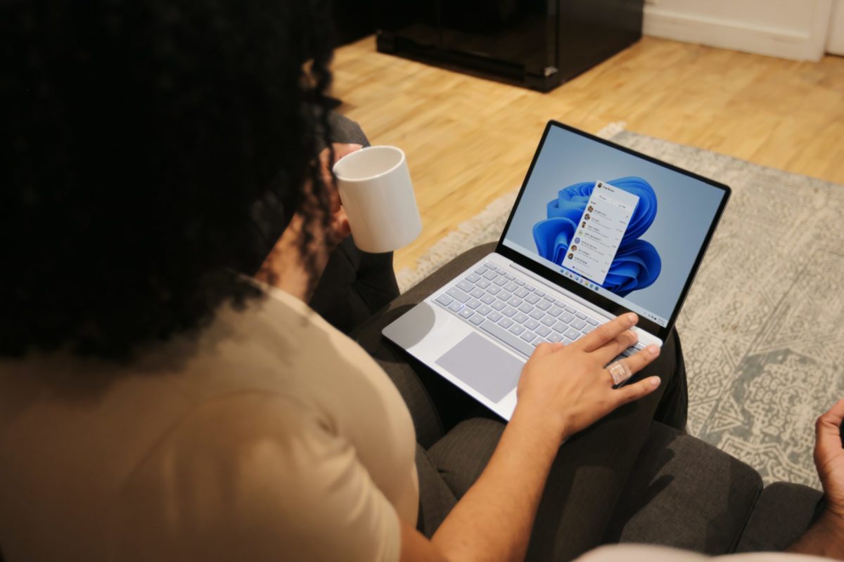 Woman working from home with Surface laptop on her lap and coffee mug in her hand