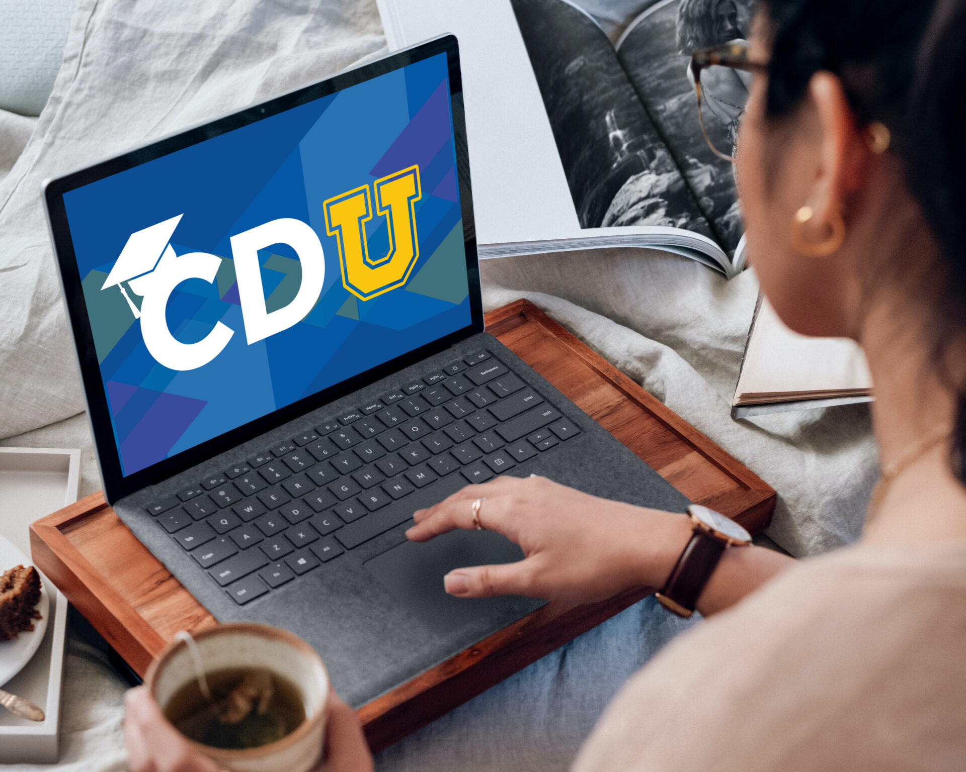 Woman sat on bed in front of her laptop, the letters CDU are visible on the screen