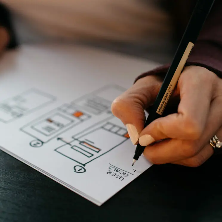 Woman drawing app design on piece of paper