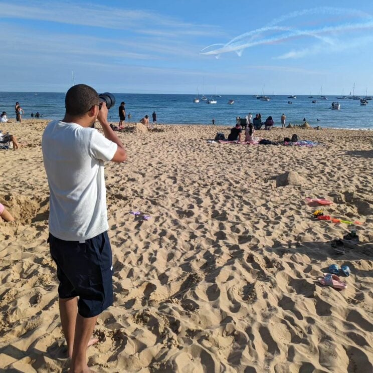 Man on a beach taking a photo of the sea.