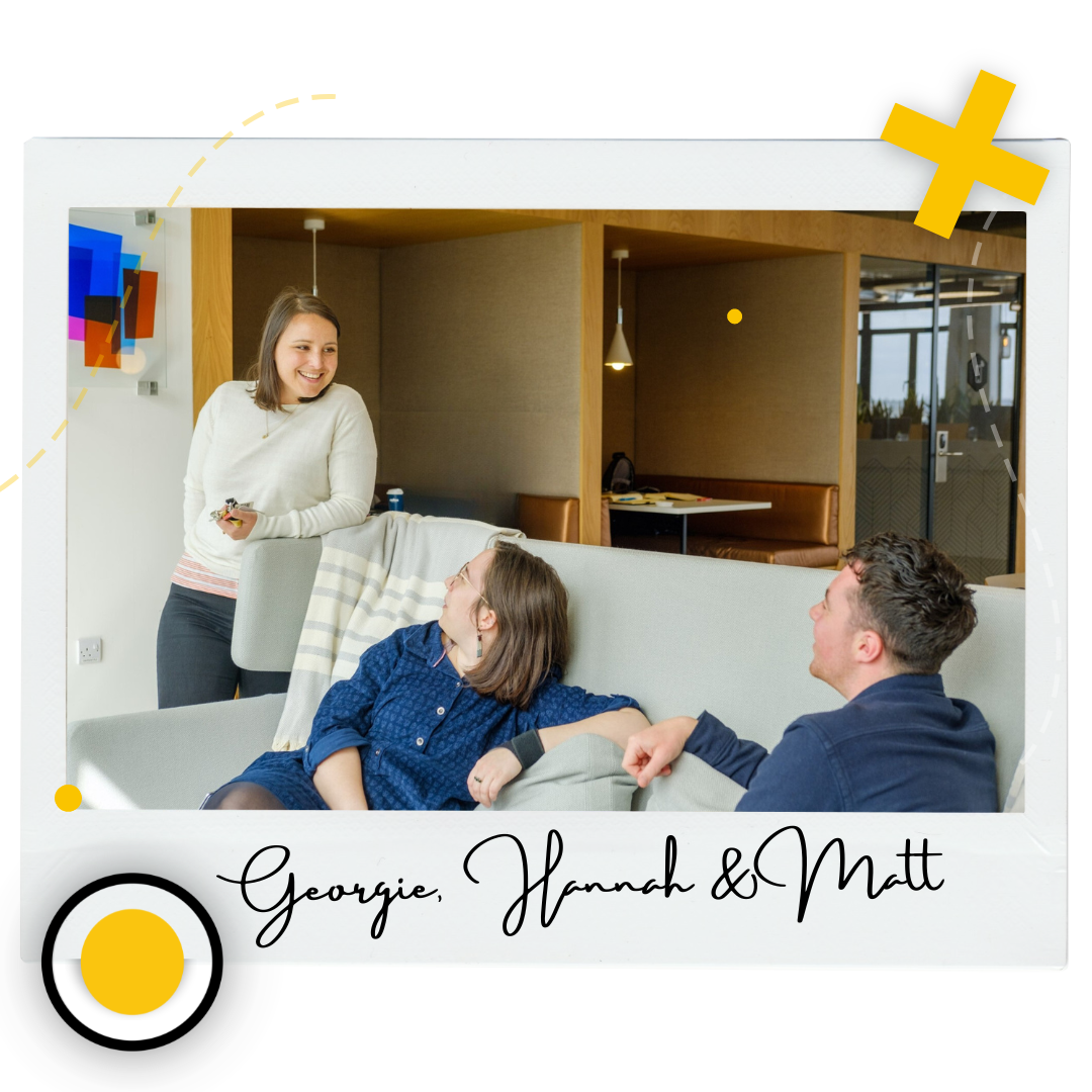 Polaroid of there are two people sitting on a sofa in a modern office space, looking up at a third woman who is smiling down at them